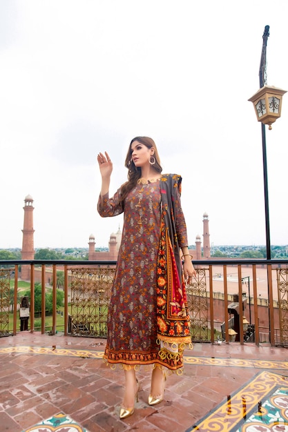 Photo girl wearing desi traditioanl dress posing on roof top badshahi mosque in background