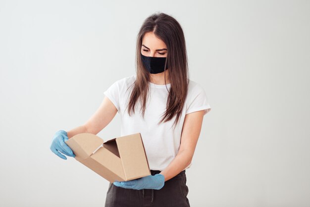 Girl wearing face mask and gloves and holding a box