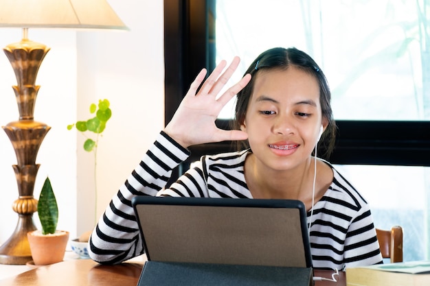 Ragazza che indossa un copricapo e studia online a casa durante la quarantena domestica.