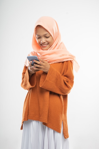 A girl wearing a hooded stands holding a cellphone