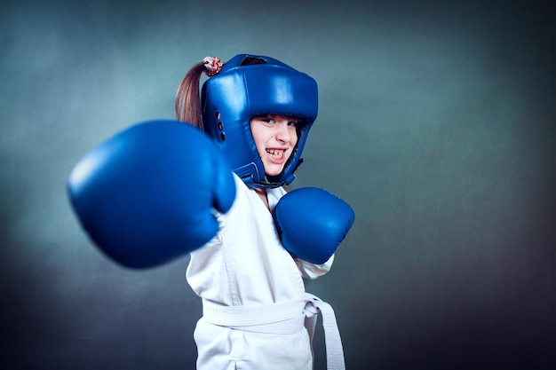 Girl wearing a karate uniform and blue boxing glove