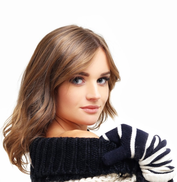 Girl wearing knit scarf and sweater posing against blue background