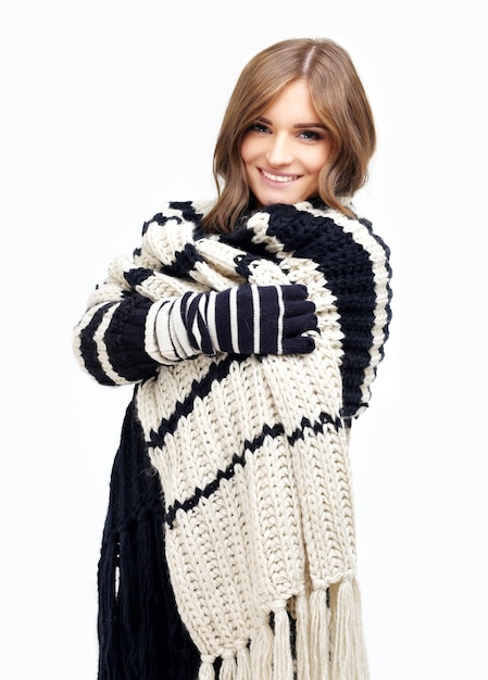 Girl wearing knit scarf and sweater posing against blue background