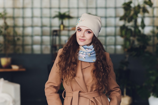 Ragazza che indossa cappello, cappotto e sciarpa caldi lavorati a maglia