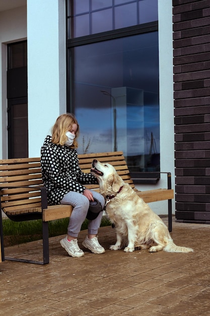 Photo girl wearing mask sitting by dog on bench