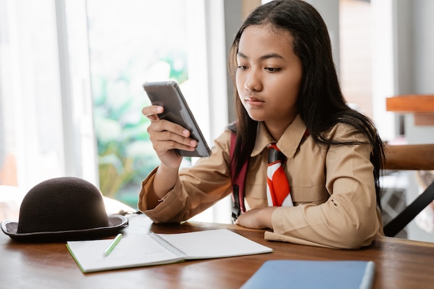Girl wearing scout uniform studying and using mobile phone
