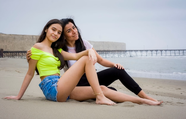 写真 夏服を着た女の子とビーチの砂浜でポーズをとる母親