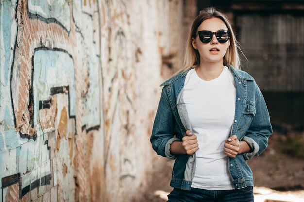 Photo girl wearing t-shirt and cotton jacket posing against street