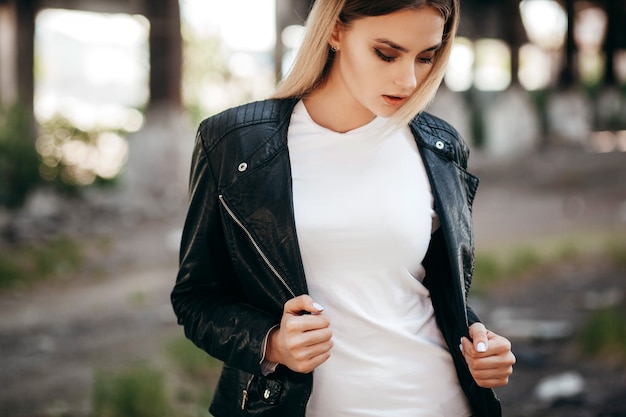 Girl wearing t-shirt and leather jacket posing against street