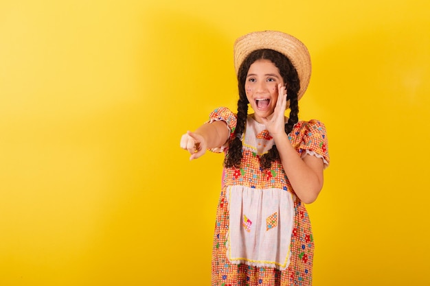 Girl wearing traditional orange clothes for festa junina Sighting and pointing to something far away incredible Promotion advertisement