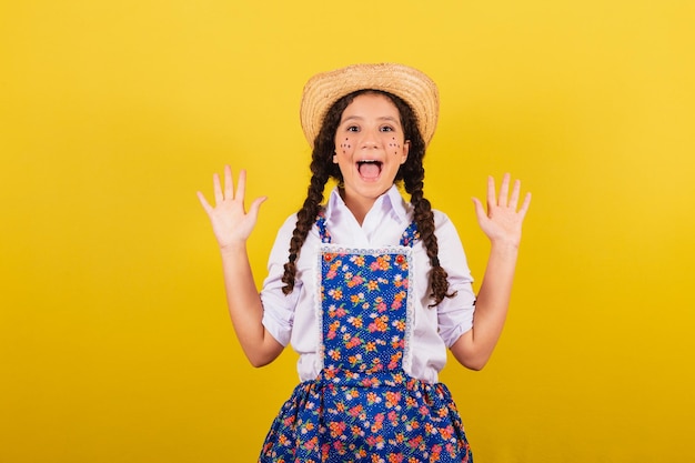 Girl wearing typical clothes for Festa Junina amazed excited with happiness and joy For the Festival do Arraia