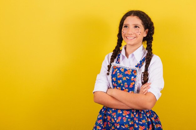 Girl wearing typical clothes for festa junina arms crossed no\
hat for the festival do arraia