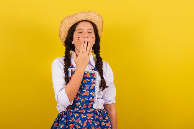 Girl wearing typical clothes for festa junina hand over mouth yawning feeling sleepy for the festival do arraia