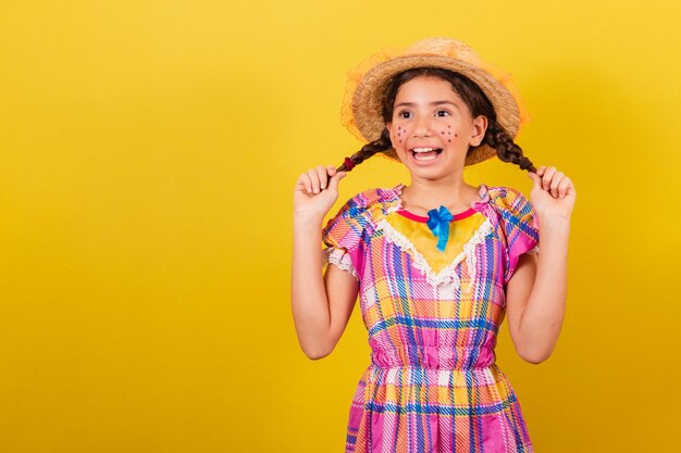 Girl wearing typical clothes for festa junina showing festa junina hairstyle dancing and smiling for the festival do arraia