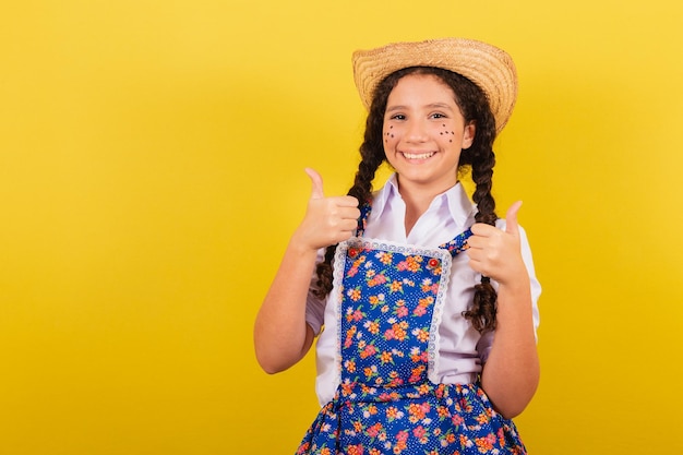 Girl wearing typical clothes for festa junina thumb up approval\
yes positive for the festival do arraia