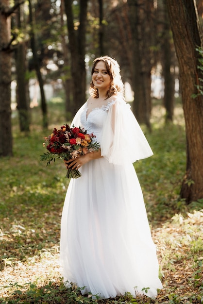 Girl in a wedding dress in the autumn forest against the background of wild trees