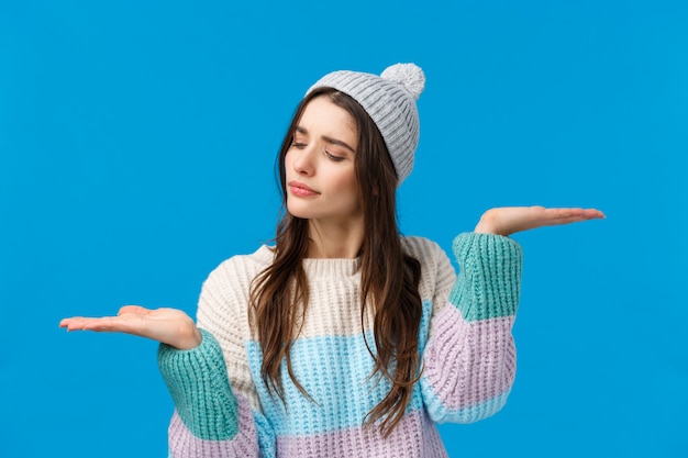 Girl weighing between to choices, making decision what buy, raising hands measuring something