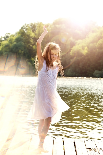 A girl in a wet white dress dancing near the river