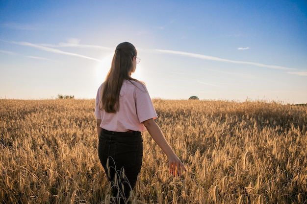 Girl in wheat field, girl's hand and wheat spikelets, sunset on field