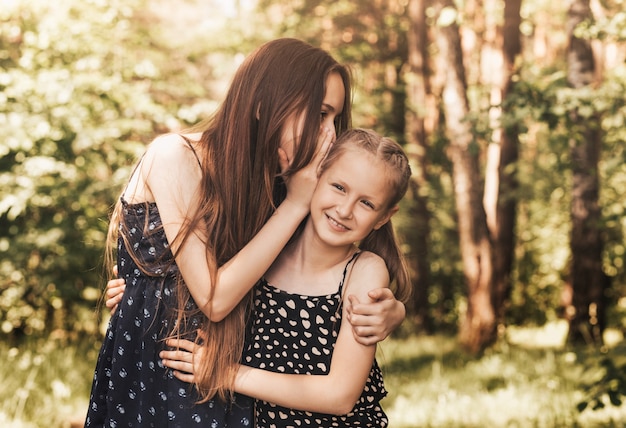 A girl whispers a secret in her sister's ear