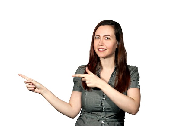 The girl on a white background looks at the viewer and points with both hands to the side