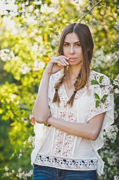 Foto ragazza in camicetta bianca si trova sullo sfondo di un melo in fiore 6105