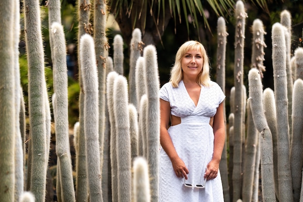 A girl in a white dress on the background of huge cacti on the island of Tenerife