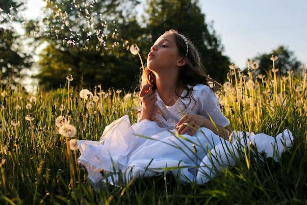 Girl in white dress blow dundelion