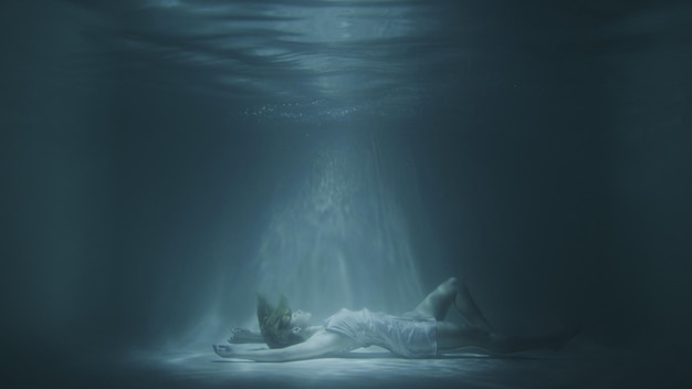 Девушка в белом платье падает под воду