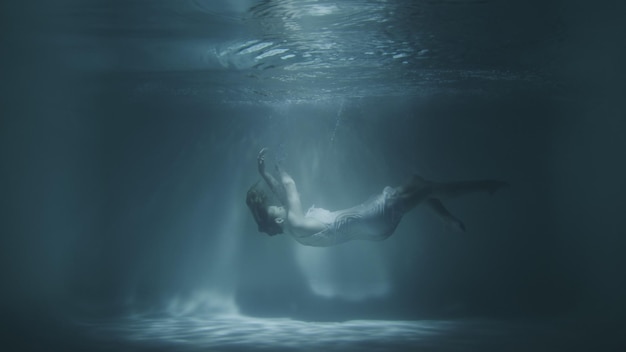 A girl in a white dress falls under the water