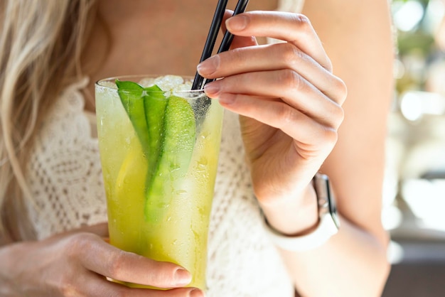 A girl in a white dress holds a cold lemonade in a glass glass in her hand