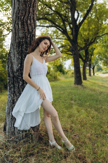 A girl in a white dress near a tree