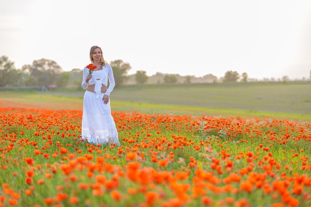 Girl in a white dress in the poppy field