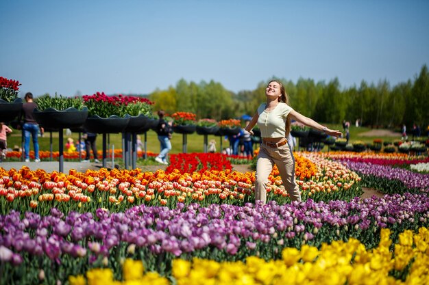 A girl in a white dress runs among the tulips Field with yellow and red tulips