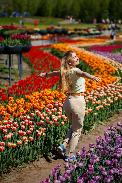 A girl in a white dress runs among the tulips Field with yellow and red tulips