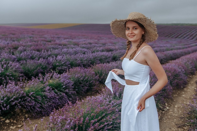 Una ragazza con un vestito bianco e un cappello di paglia in un campo di lavanda