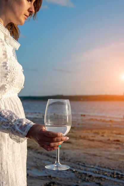 Girl in a white dress with a glass of wine.