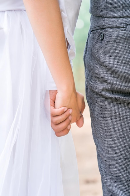 Photo a girl in a white dress with a man holding hands