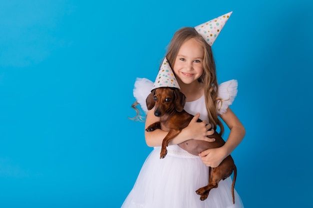 Ragazza in un vestito bianco soffice ed elegante con un cane bassotto in braccio