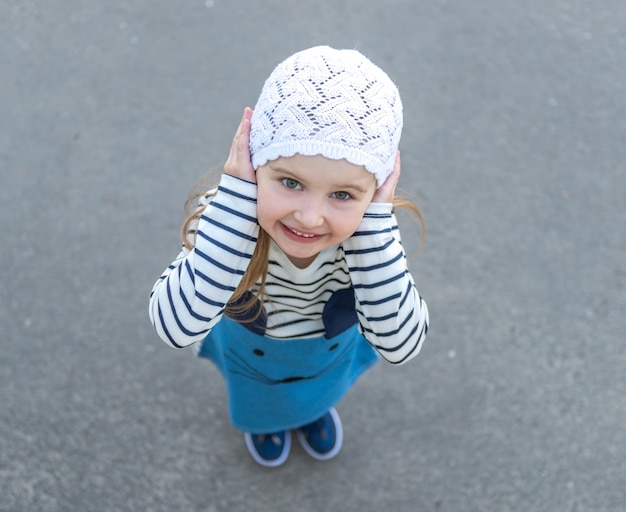 Girl in white hat standing outside, smiling