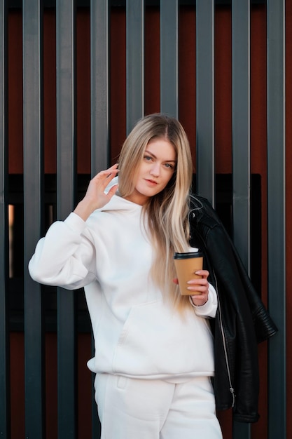 Ragazza con una felpa con cappuccio bianca con caffè da asporto