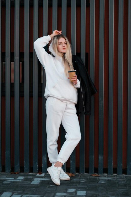 Foto ragazza con una felpa con cappuccio bianca con caffè da asporto