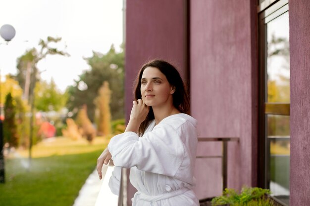 Girl in a white hotel coat in a hotel on the balcony belt portrait