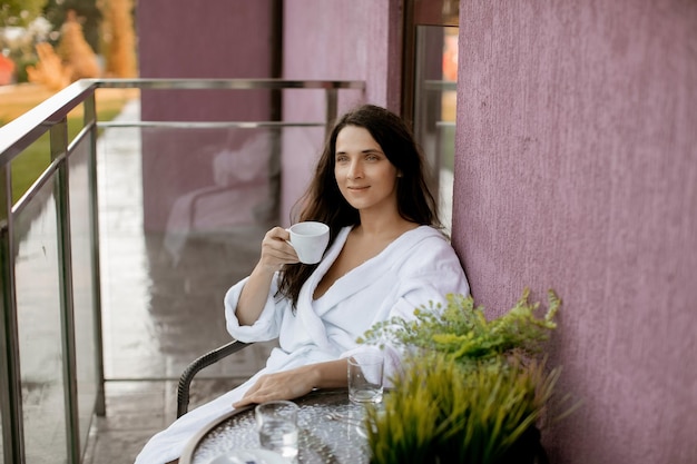 Girl in a white hotel coat in a hotel on the balcony belt\
portrait