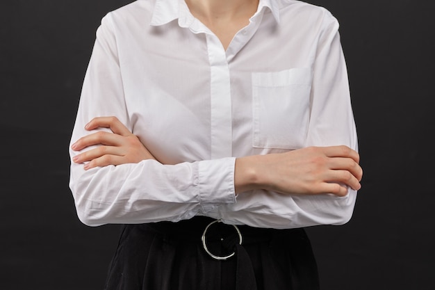 Girl in a white shirt clasped hands on a black background.