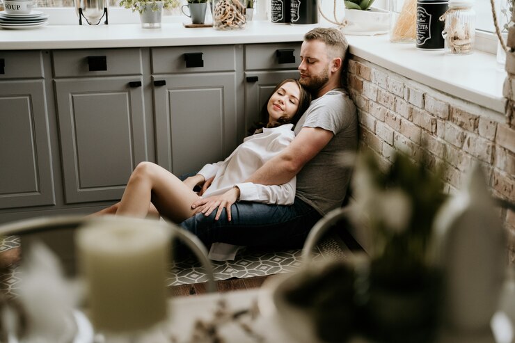 Photo girl in a white shirt and a guy in a gray t-shirt in the kitchen. kiss and hug.
