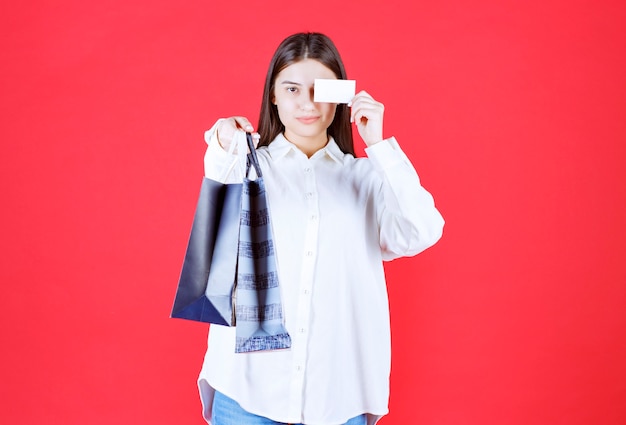 Girl in white shirt holding multiple shopping bags and presenting her business card