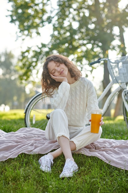 A girl in white sitting on a grass in the park