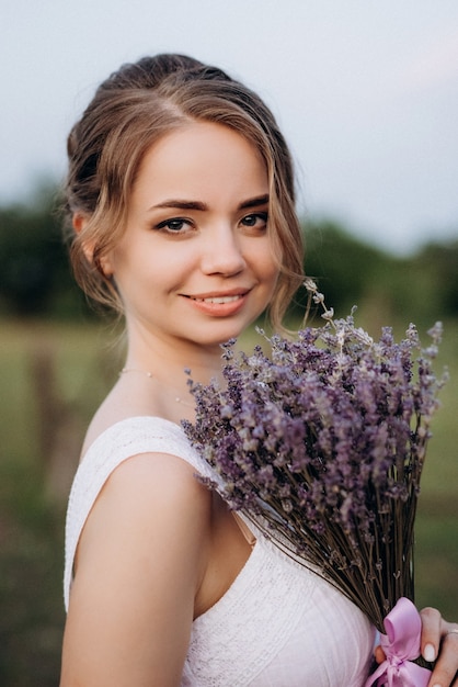 Girl in a white sundress and a guy in a white shirt on a walk at sunset with a bouquet in a village outside the city