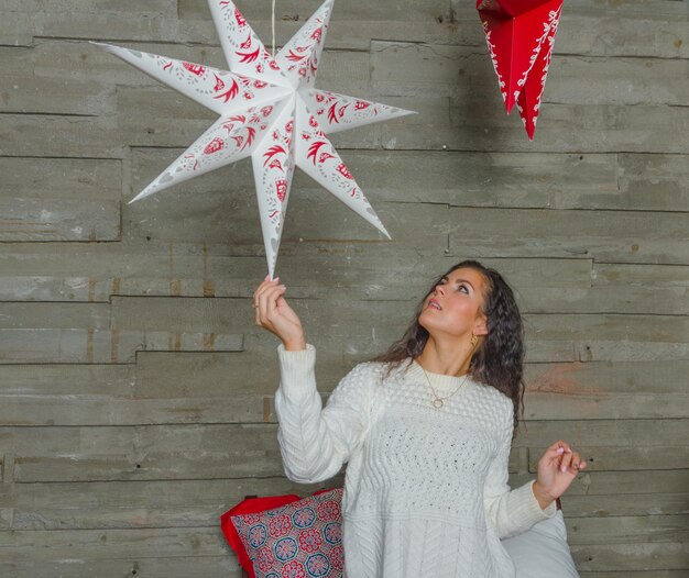 The girl in the white sweater in bed playing with the decoration of the Christmas star.